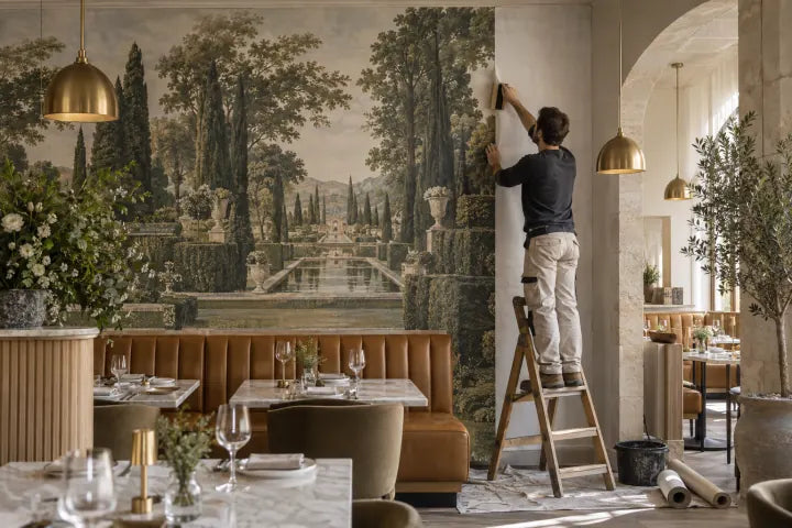 Un poseur maroufle un lé de panoramique de jardin dans la salle d’un restaurant
